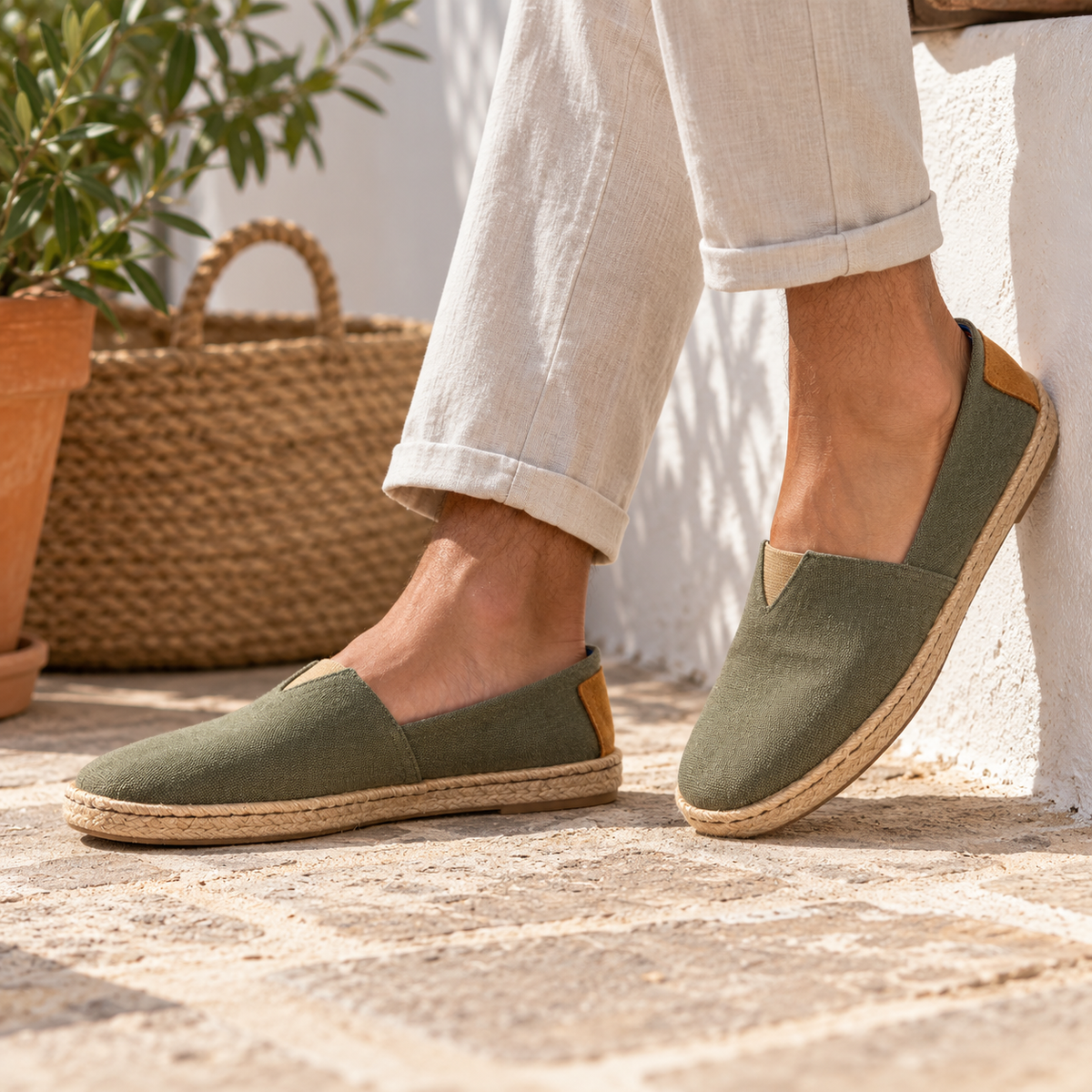 Alpargatas de hombre en color verde oliva con suela de yute, llevadas con pantalón claro en un ambiente mediterráneo.