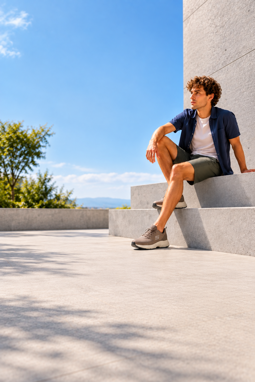 Hombre con sneakers taupe sentado en una arquitectura moderna y luminosa